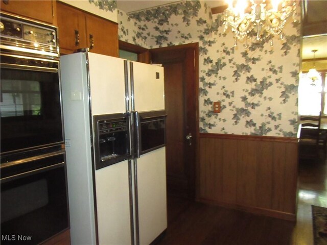64 S Cadillac Dr, Boardman, OH 44512 - kitchen featuring white fridge with ice dispenser, wallpapered walls, a wainscoted wall, a chandelier, and brown cabinetry