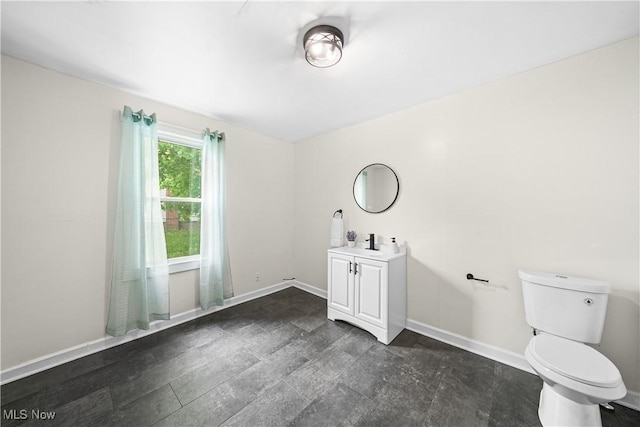 bathroom featuring toilet, vanity, and baseboards