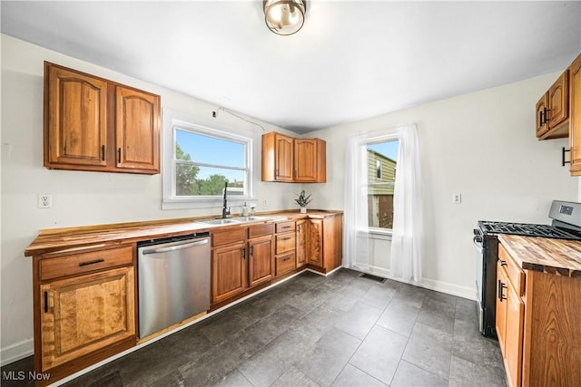 kitchen featuring appliances with stainless steel finishes, butcher block counters, a sink, and healthy amount of natural light