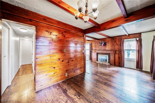 3509 Fargo Dr, Ashtabula, OH 44004 - unfurnished living room featuring a textured ceiling, wooden walls, beamed ceiling, wood-type flooring, and a glass covered fireplace