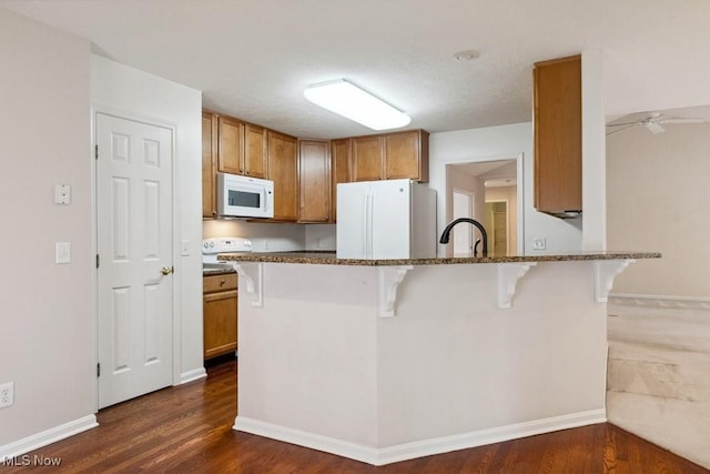 1250 Spring Ridge Cir, Alliance, OH 44601 - kitchen featuring white appliances, a breakfast bar, dark stone counters, and dark wood finished floors