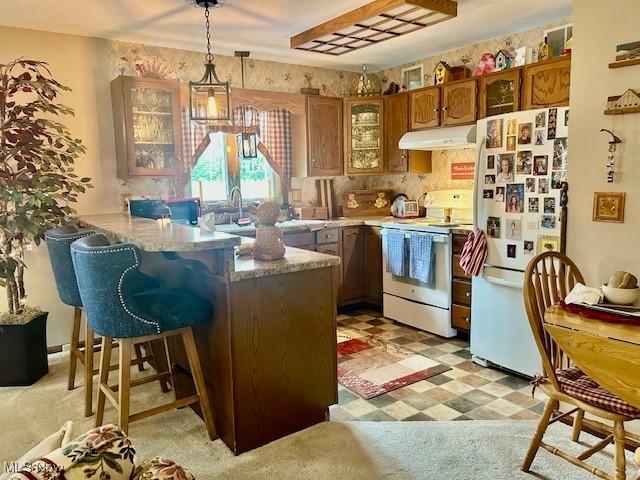 1845 Meadow Ln Unit B, Salem, OH 44460 - kitchen with white appliances, under cabinet range hood, brown cabinetry, a peninsula, and glass insert cabinets