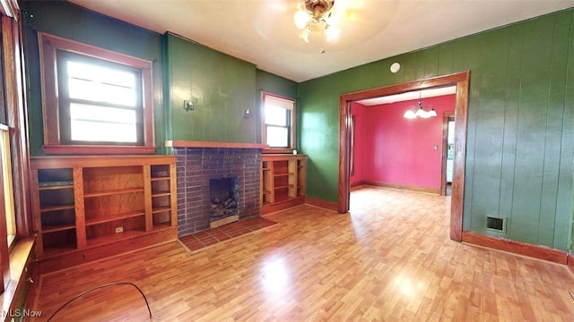 1632 Lawrence St, Parkersburg, WV 26101 - unfurnished living room featuring wood finished floors, a brick fireplace, a ceiling fan, wooden walls, and baseboards