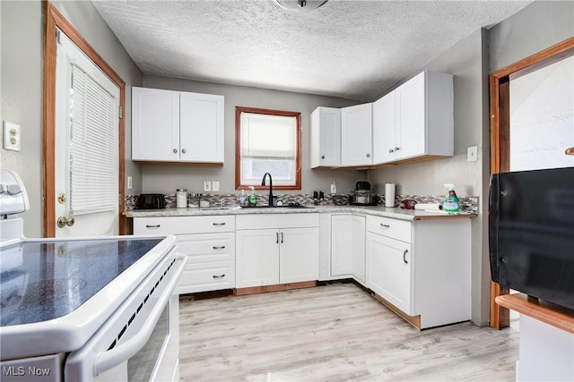 kitchen with white range with electric stovetop, a sink, white cabinetry, light wood finished floors, and a textured ceiling