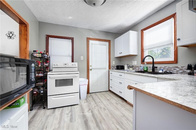 kitchen with electric stove, a sink, light wood-style floors, white cabinets, and light countertops