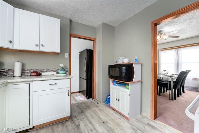 kitchen featuring black appliances, a textured ceiling, light wood-style floors, white cabinetry, and ceiling fan