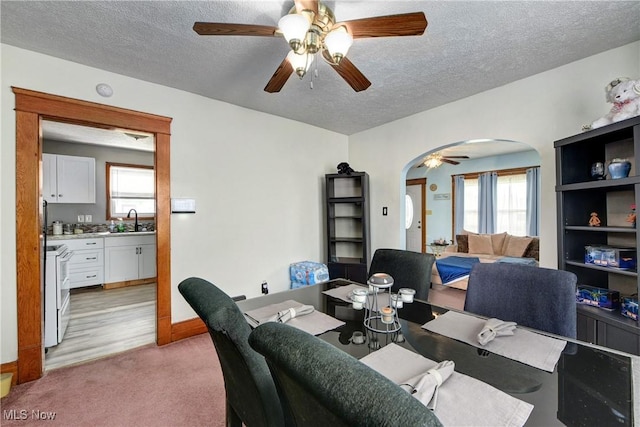 home office with arched walkways, a sink, a textured ceiling, ceiling fan, and healthy amount of natural light