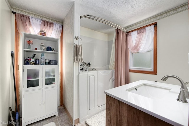bathroom featuring a textured ceiling, a tub, curtained shower, washer / dryer, and vanity