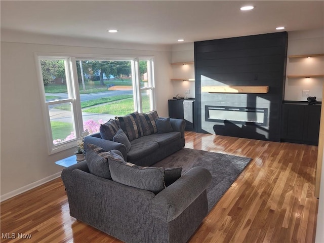 living area with a large fireplace, light wood-style flooring, recessed lighting, and baseboards