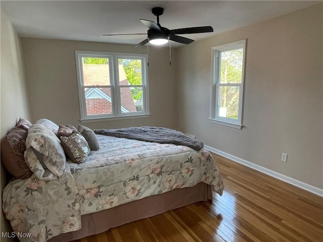 bedroom featuring baseboards, wood finished floors, and a ceiling fan