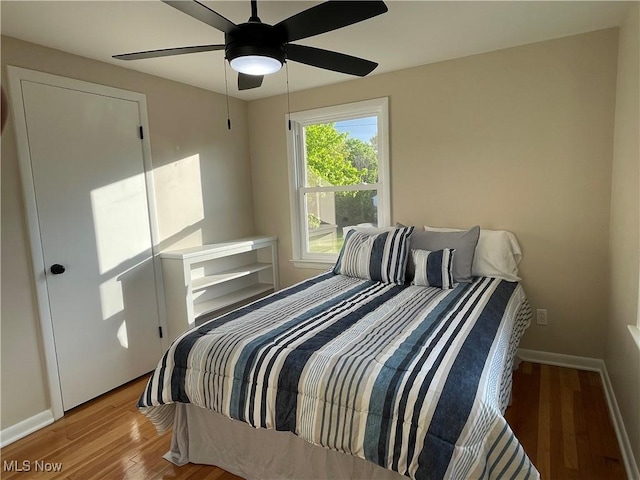 bedroom featuring wood finished floors, baseboards, and ceiling fan