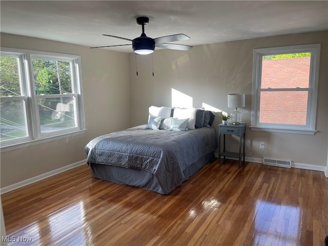 bedroom with hardwood / wood-style flooring, multiple windows, and baseboards