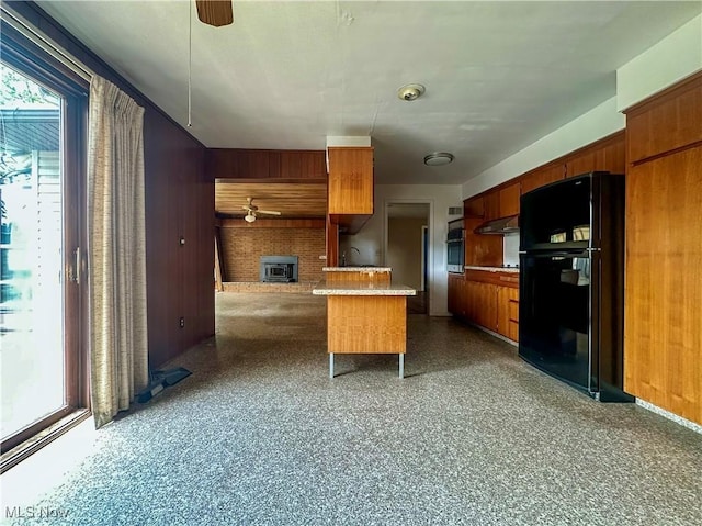 1357 Kearney St, Niles, OH 44446 - kitchen with freestanding refrigerator, oven, ceiling fan, brown cabinetry, and wooden walls