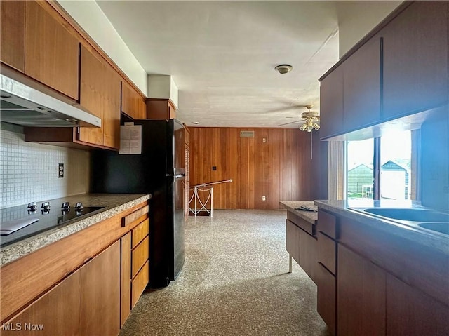 1357 Kearney St, Niles, OH 44446 - kitchen with black electric cooktop, under cabinet range hood, ceiling fan, tasteful backsplash, and wooden walls