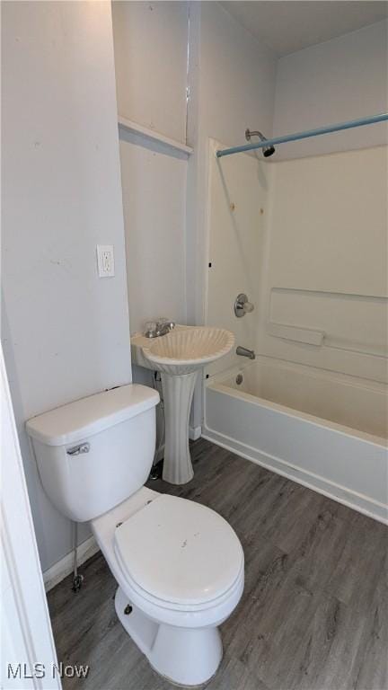 bathroom with wood finished floors, bathing tub / shower combination, and toilet