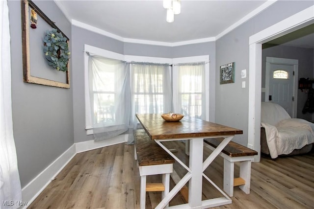 dining area with wood finished floors, crown molding, and baseboards