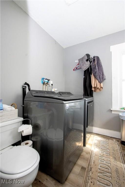 bathroom with wood finished floors, toilet, washer and clothes dryer, vaulted ceiling, and baseboards