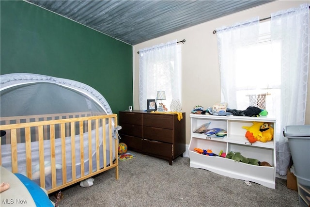 bedroom featuring carpet and a nursery area
