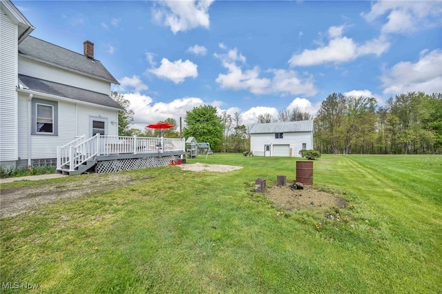 view of green lawn featuring a wooden deck and an outbuilding
