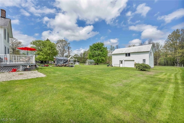 view of grassy yard with an outbuilding, a wooden deck, and a garage