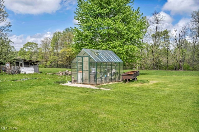 view of grassy yard with a greenhouse and an outdoor structure