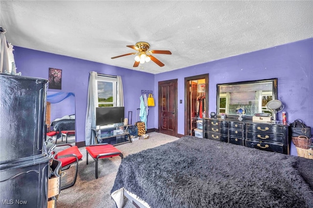 carpeted bedroom featuring a textured ceiling, a ceiling fan, and baseboards