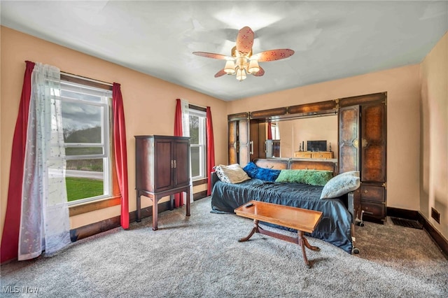 carpeted bedroom featuring multiple windows, baseboards, and ceiling fan