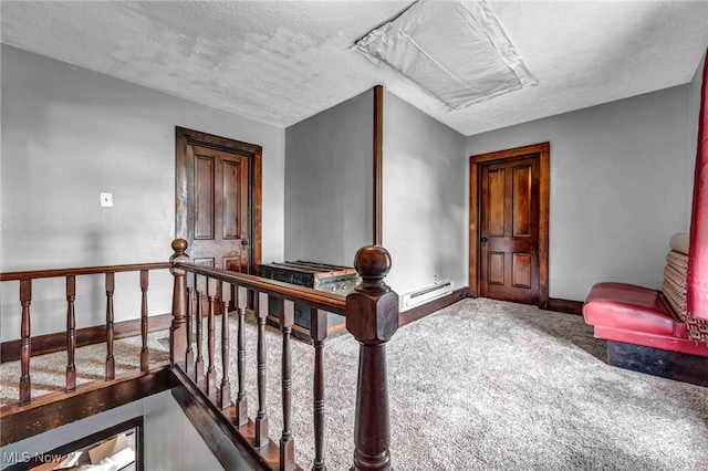 corridor featuring carpet, an upstairs landing, baseboards, and a textured ceiling