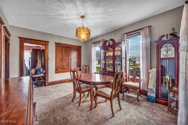 carpeted dining area with a chandelier and baseboards