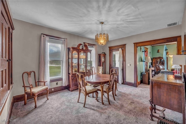 dining area featuring a chandelier, light colored carpet, and baseboards