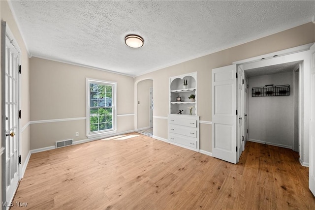 149 Sand Run Rd, Akron, OH 44313 - unfurnished bedroom featuring light wood-style floors, arched walkways, a textured ceiling, and baseboards