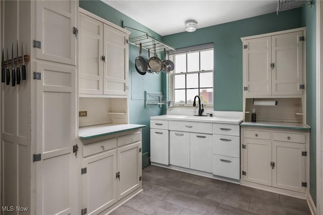 kitchen featuring a sink, light countertops, tile patterned floors, and white cabinets