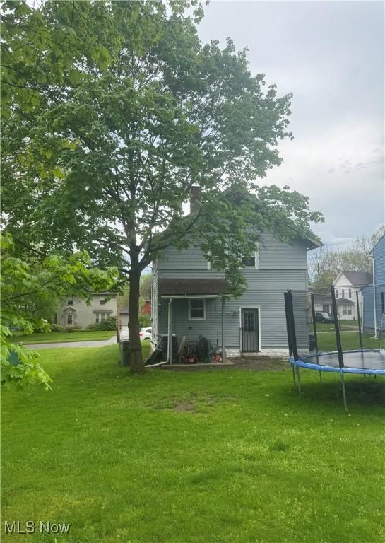 2574 Mount Vernon Ave, Youngstown, OH 44502 - back of property with a trampoline, a yard, and a chimney