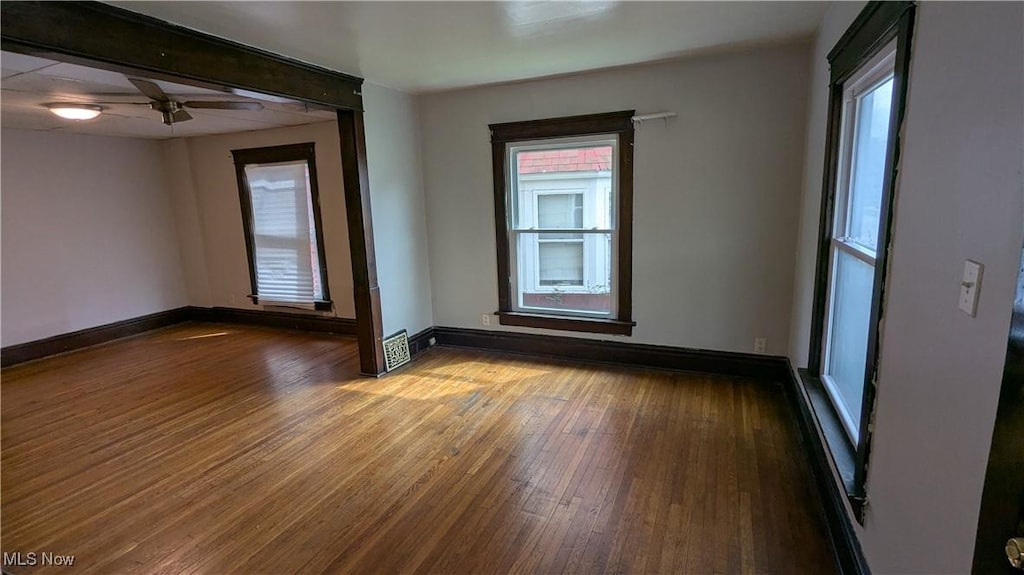 empty room featuring wood finished floors, baseboards, and a ceiling fan