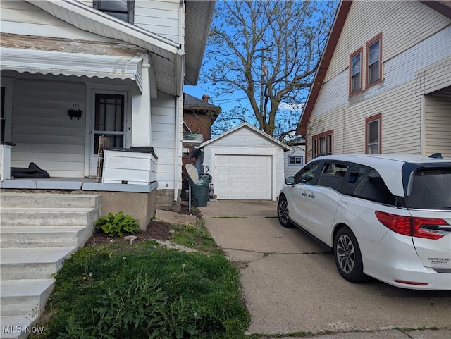 view of side of property with an outdoor structure, driveway, and a detached garage