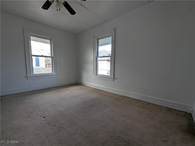 carpeted empty room featuring ceiling fan and baseboards