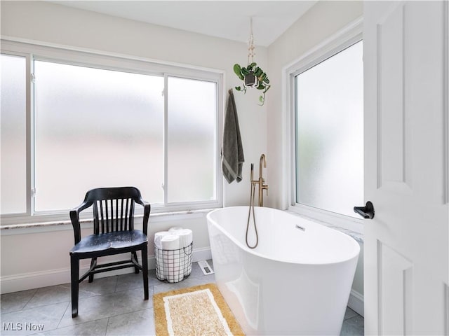 bathroom featuring baseboards, a soaking tub, and tile patterned flooring