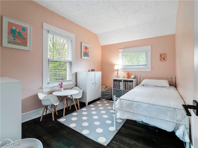 bedroom featuring wood finished floors, vaulted ceiling, multiple windows, a textured ceiling, and baseboards