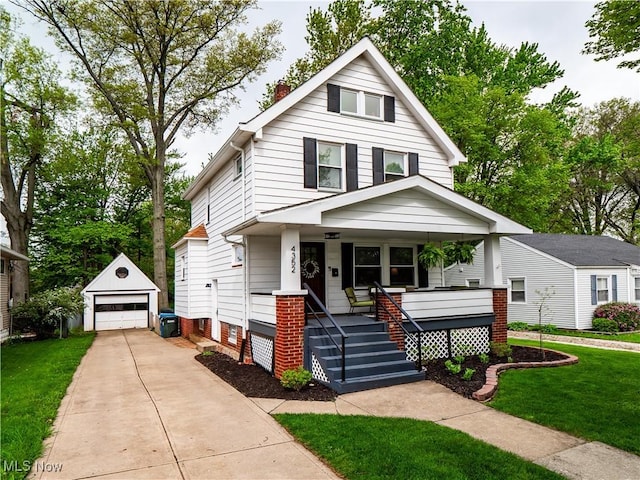 traditional style home with an outbuilding, a detached garage, a porch, a front lawn, and concrete driveway