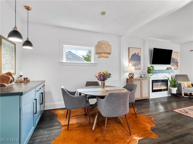 dining area with dark wood finished floors, a glass covered fireplace, baseboards, and crown molding