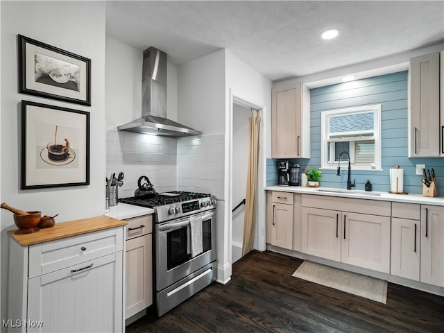 kitchen featuring gas stove, wall chimney range hood, a sink, light countertops, and backsplash