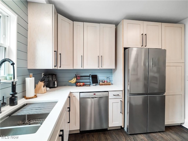 kitchen with stainless steel appliances, a sink, light countertops, and dark wood finished floors