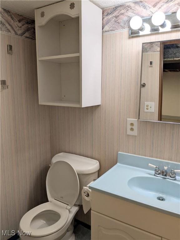half bath featuring wallpapered walls, toilet, and vanity