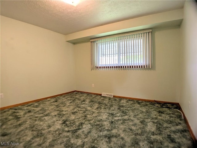 carpeted spare room with a textured ceiling and baseboards