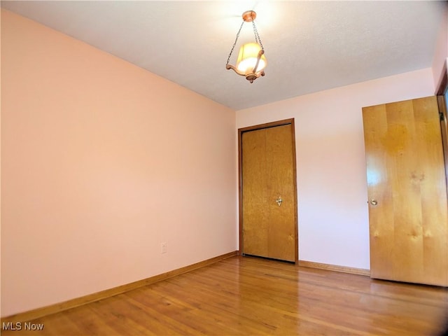 unfurnished bedroom with wood finished floors, baseboards, and a closet