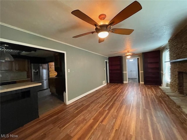 1585 County Road 9, Marietta, OH 45750 - unfurnished living room featuring dark wood-style flooring, ceiling fan, baseboards, ornamental molding, and a stone fireplace