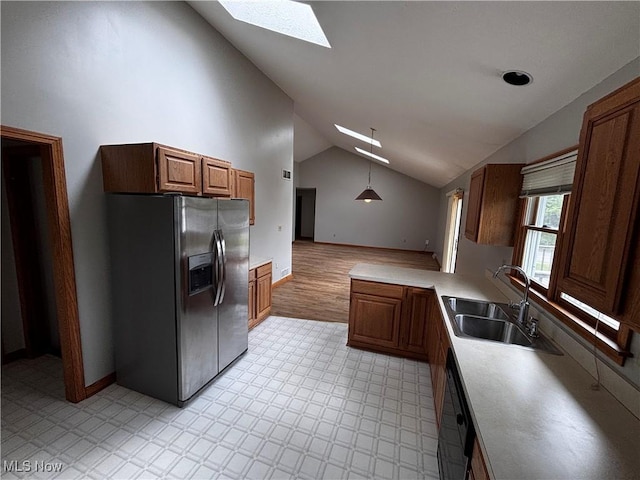 kitchen featuring stainless steel fridge, a skylight, a sink, vaulted ceiling, and decorative light fixtures