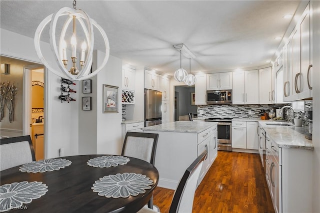 5500 12th Ave, Vienna, WV 26105 - kitchen with appliances with stainless steel finishes, a sink, tasteful backsplash, white cabinetry, and a kitchen island