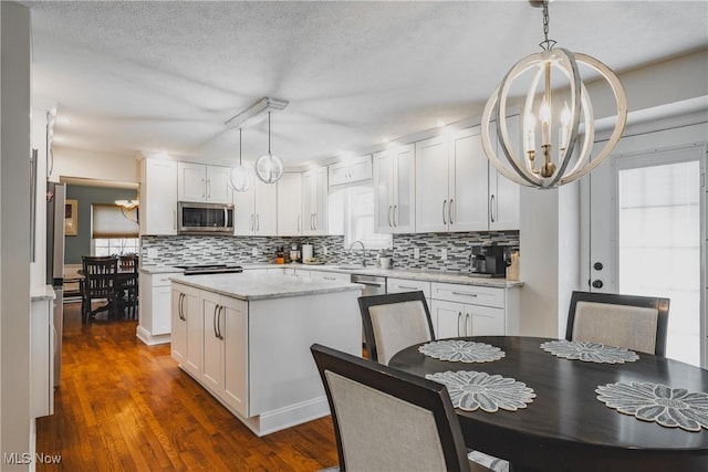 5500 12th Ave, Vienna, WV 26105 - kitchen featuring stainless steel microwave, a chandelier, decorative backsplash, white cabinets, and a kitchen island