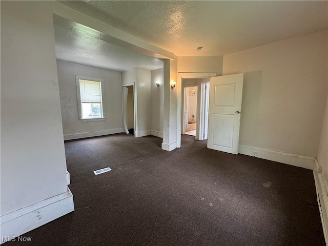 12423 Phillips Ave, Cleveland, OH 44108 - empty room featuring dark colored carpet, baseboards, and a textured ceiling